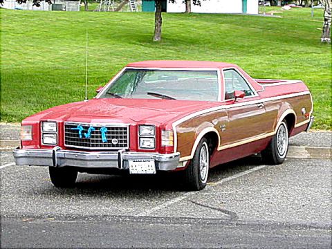 1967 Ford Ranchero - This red pickup truck features wood paneling on its sides and is parked in a lot with a grassy area in the background.