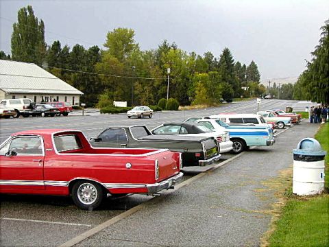 1967 Ford Ranchero - A red 1967 Ford Ranchero is parked in a lot alongside other vehicles under a cloudy sky.