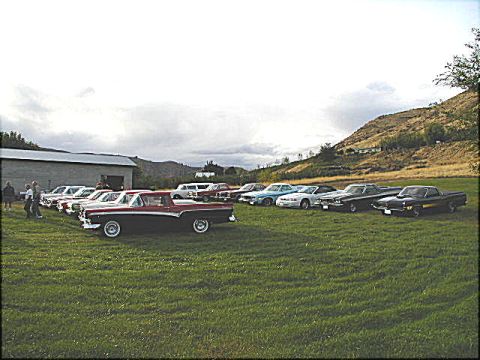 1967 Ford Ranchero - A collection of classic cars are gathered on a grassy field with a barn and hills in the background.