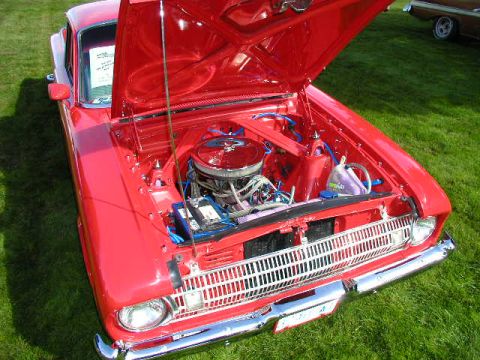 1967 Ford Ranchero - A bright red 1965 Ford Falcon is displayed with its hood open, revealing the engine bay.