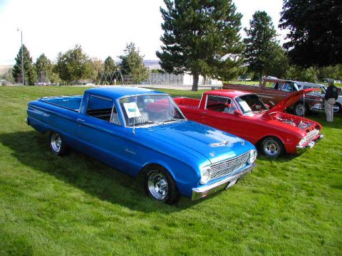 1967 Ford Ranchero - A blue 1960s pickup truck is parked on a grassy field next to other vehicles.