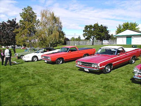 1967 Ford Ranchero - Several Ford Rancheros are lined up on a grassy field under a partly cloudy sky.