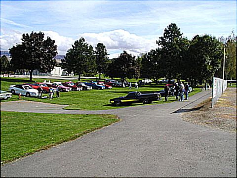 1967 Ford Ranchero - A group of classic cars are gathered on a grassy field under a partly cloudy sky.