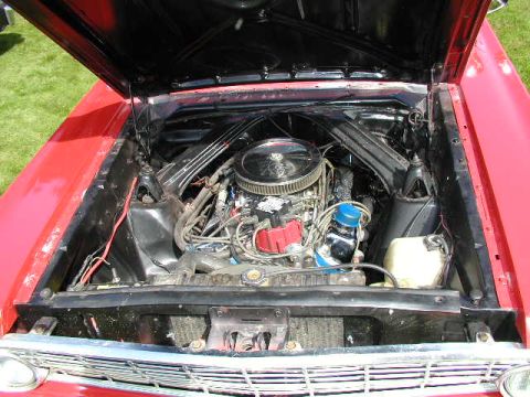 1967 Ford Ranchero - The engine bay of a red 1967 Ford Ranchero, a V8 engine with a chrome air cleaner and red distributor cap.