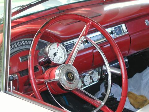 1967 Ford Ranchero - The interior of a classic car features a red steering wheel and dashboard with multiple gauges and a radio.