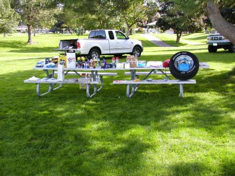 1967 Ford Ranchero - Two pickup trucks are visible in a park setting, with picnic tables laden with items between them.