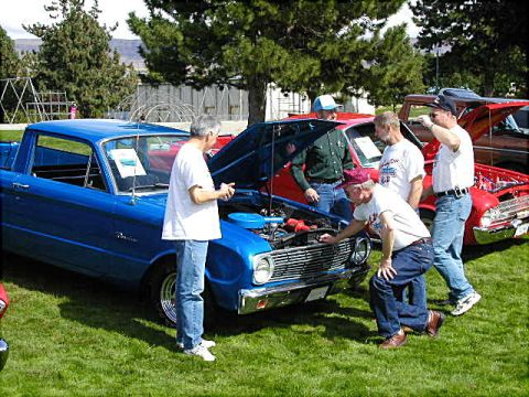 1967 Ford Ranchero - People gather around a blue 1967 Ford Ranchero, inspecting its engine at an outdoor car event.