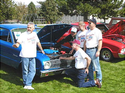 1967 Ford Ranchero - A group of men examine the engine of a blue 1967 Ford Ranchero at a car show.