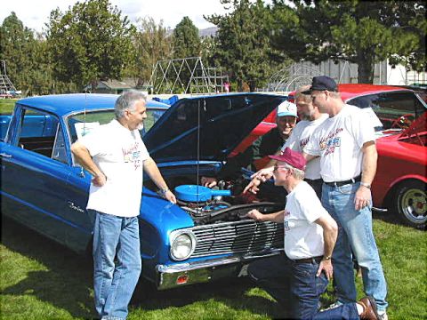 1967 Ford Ranchero - Men examine the engine of a blue 1967 Ford Ranchero at an outdoor car show.