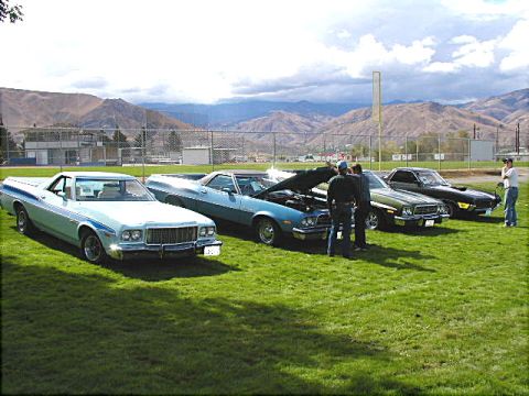 1967 Ford Ranchero - A light blue 1977 Ford Ranchero with distinctive blue side stripes is displayed alongside other vehicles.