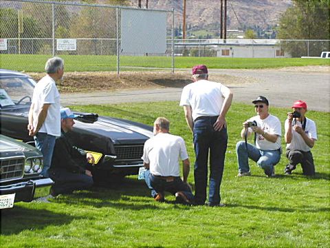 1967 Ford Ranchero - Several men examine a 1969 Chevrolet Camaro and another classic vehicle on a sunny day.