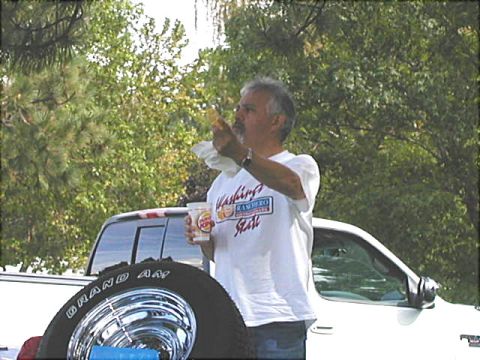 1967 Ford Ranchero - A man enjoys a snack and drink outdoors, with a white truck and spare tire visible.