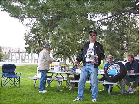1967 Ford Ranchero - An outdoor gathering with people and picnic tables, a prominent tire display.