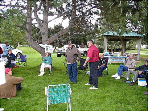 1967 Ford Ranchero - An outdoor gathering with several people relaxing on the grass and some vehicles visible in the background.