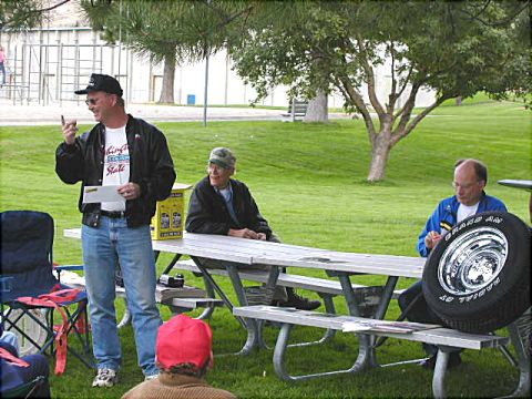 1967 Ford Ranchero - Outdoor gathering with people seated at picnic tables and a tire displayed.