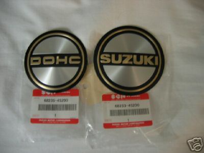 1985 Ford LTD Crown Victoria - Two Suzuki emblems, one for DOHC and one with the brand name, are shown with their part number tags.