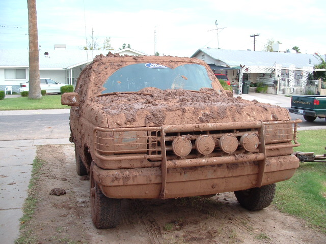 Mud-covered 1990 Ford Bronco front view with four auxiliary lights