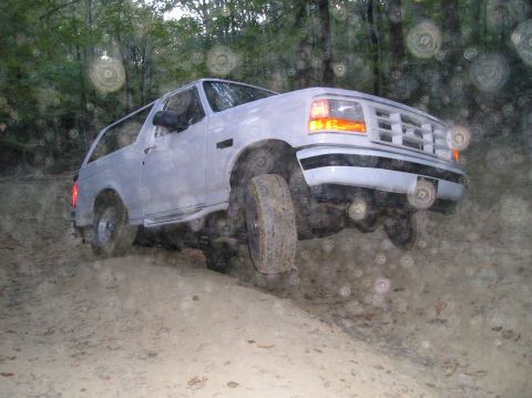 1996 Ford Bronco - 1996 Ford Bronco navigating a sandy, wooded trail.