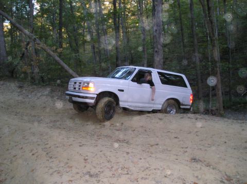 1996 Ford Bronco - A white Ford Bronco navigates a sandy, wooded trail.