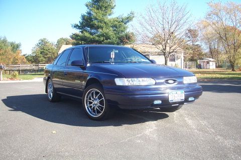 1993 Ford Taurus - A dark blue 1993 Ford Taurus is shown from a 3q-front angle, aftermarket chrome wheels.