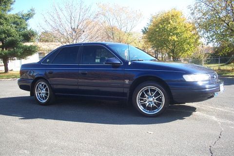 1993 Ford Taurus - Side view of a 1993 Ford Taurus sedan with custom wheels.