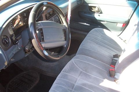 1993 Ford Taurus - The interior of a 1993 Ford Taurus shows gray cloth seats and a dashboard with a Ford steering wheel.