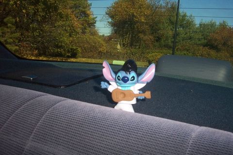 1993 Ford Taurus - A Stitch toy dressed as Elvis Presley sits on the back seat of a car, with trees visible through the rear window.