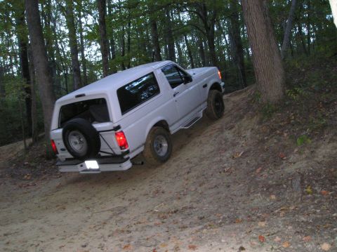 1996 Ford Bronco - White 1996 Ford Bronco navigating a wooded trail.