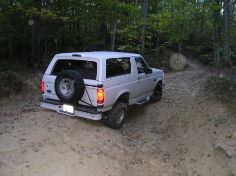 1996 Ford Bronco - White 1996 Ford Bronco navigates a wooded dirt path.