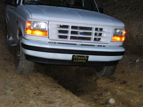 1996 Ford Bronco - A white Ford Bronco navigates a rough dirt path, its front grille and headlights clearly visible.