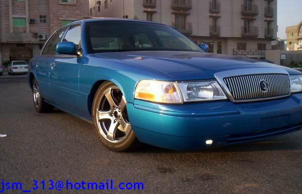 Teal blue Mercury sedan, 3/4 front view on chrome multi-spoke wheels