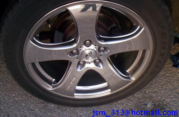 Close-up of a chrome five-spoke aftermarket wheel with a KH logo in the center