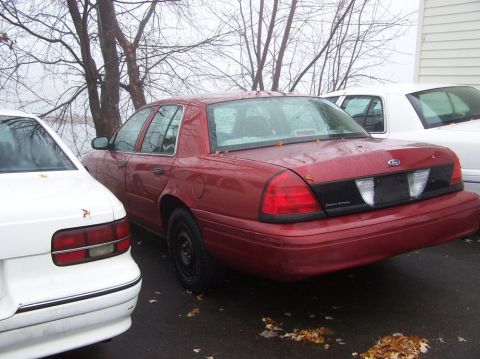 2001 Ford Crown Victoria - Rear view of a red 2001 Ford Crown Victoria parked next to another vehicle.