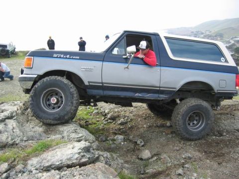 1989 Ford Bronco - Modified 1989 Ford Bronco tackles a challenging rocky trail with a person inside.