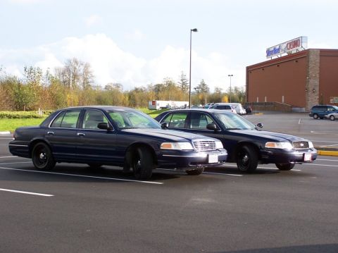 1998 Ford Crown Victoria - Two dark blue 1998 Ford Crown Victoria sedans are parked in a lot near a casino.