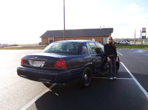 2001 Ford Crown Victoria - A woman poses next to a dark blue 2001 Ford Crown Victoria in a parking lot.