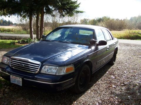 1998 Ford Crown Victoria - This 1998 Ford Crown Victoria is seen from a three-quarter front view, parked on a gravel surface under trees.