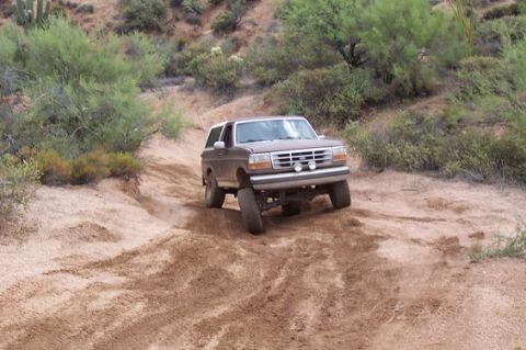 1993 Ford Bronco - A brown Ford Bronco navigates a dusty off-road path.