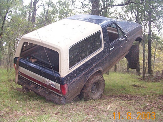 1978 Ford Bronco tilted in mud, rear quarter view