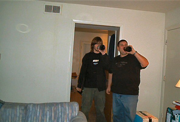 Two men drinking from bottles in a room