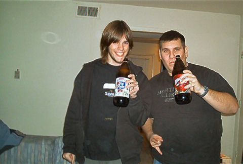 1985 Ford LTD Crown Victoria - Two men pose for a photo while holding large beer bottles.