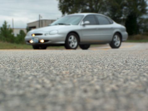 1998 Ford Taurus - A silver 1998 Ford Taurus sedan is captured from a low angle on a paved road.