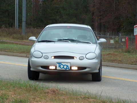 1998 Ford Taurus - A silver sedan is viewed from the front, displaying a TCCA license plate and aftermarket fog lights.