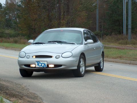 1998 Ford Taurus - A silver 1998 Ford Taurus is seen from the front-three-quarter angle on a paved road.