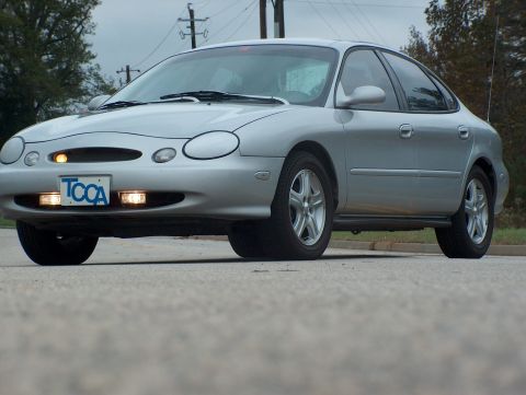 1998 Ford Taurus - A silver 1998 Ford Taurus is parked on a street with a TCCA license plate visible.