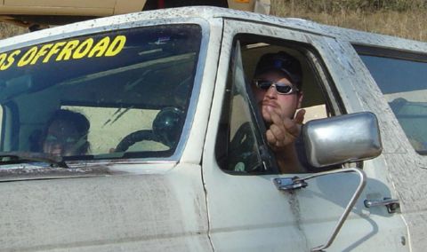 1993 Ford Bronco - Driver of a mud-splattered SUV gives the finger while a passenger looks on from the side.