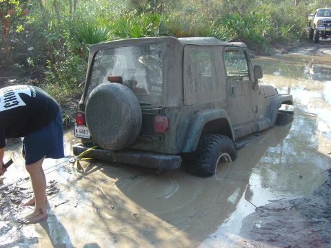 1993 Ford Bronco - A Jeep Wrangler is stuck in deep mud while another vehicle waits nearby.