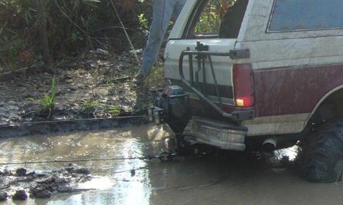 1993 Ford Bronco - This 1993 Ford Bronco is seen stuck in a muddy off-road situation, equipped with a winch for recovery.