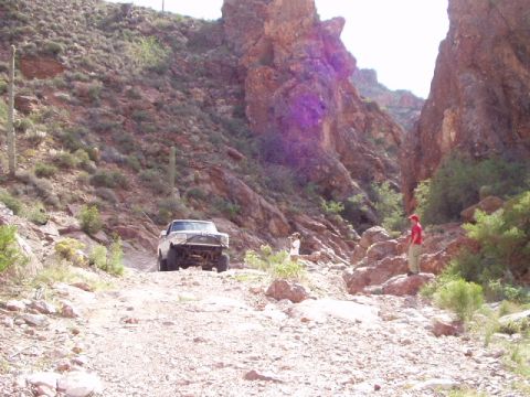 1993 Ford Bronco - Off-road vehicle navigates a challenging rocky path in a desert canyon landscape.