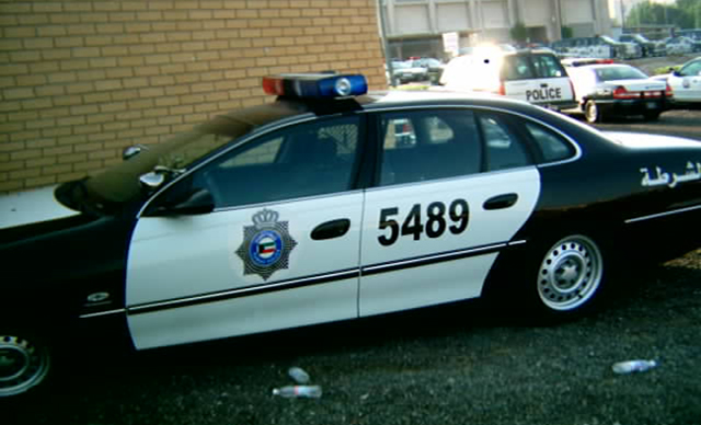Black and white Kuwait police sedan number 5489 with roof light bar and door crest